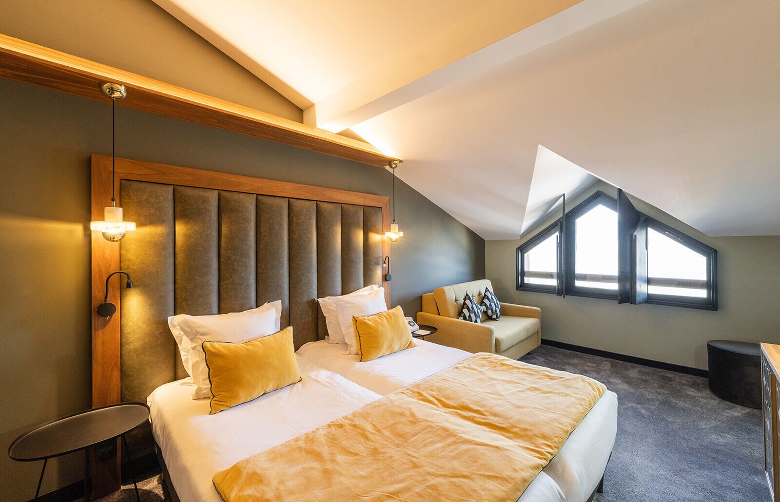 Habitación de hotel con una cama grande, un sofá, una mesita y una ventana con vistas.
