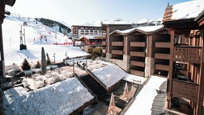 A ski resort with wooden buildings, a ski lift, and a snow-covered mountain in the background. - Fahrenheit seven Courchevel (Courchevel)