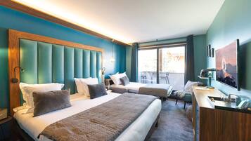 A hotel room with two beds, a desk, a TV, and a balcony with a view.