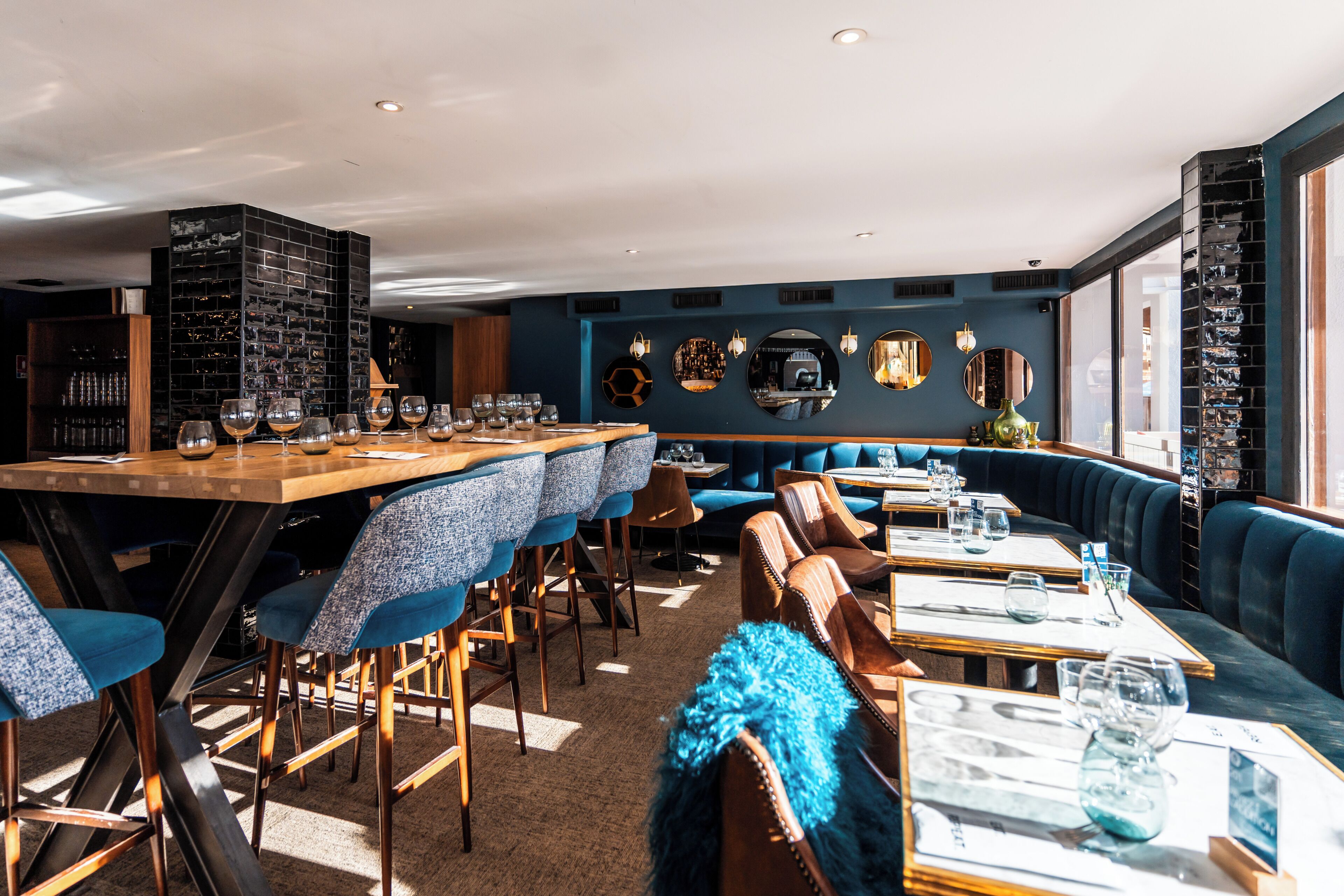 A restaurant with a bar area, seating arrangements, and a wall with decorative mirrors and a hexagonal mirror.