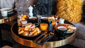 A breakfast tray with croissants, eggs, bacon, and orange juice on a round table. - Fahrenheit seven Courchevel (Courchevel)