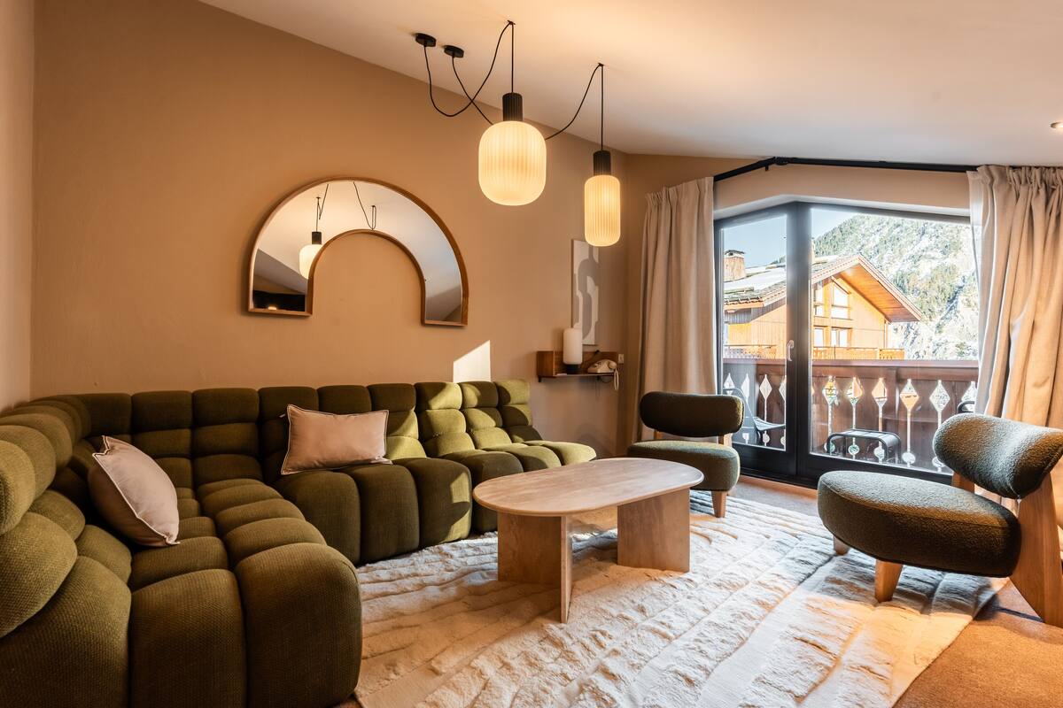 A modern living room with a sectional sofa, a wooden coffee table, and a view of a mountain through large windows.
