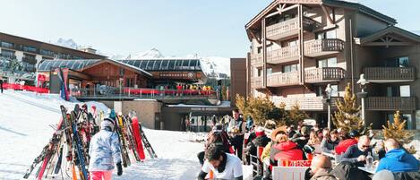 A ski resort with a wooden building, a ski lift, and a crowd of people.