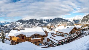 A snow-covered mountain village with wooden buildings, a ski slope, and a view of snow-capped mountains. - Fahrenheit seven Courchevel (Courchevel)