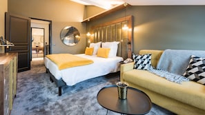 A hotel room with a bed, a sofa, a coffee table, a mirror, and a wooden headboard. - Fahrenheit seven Courchevel (Courchevel)