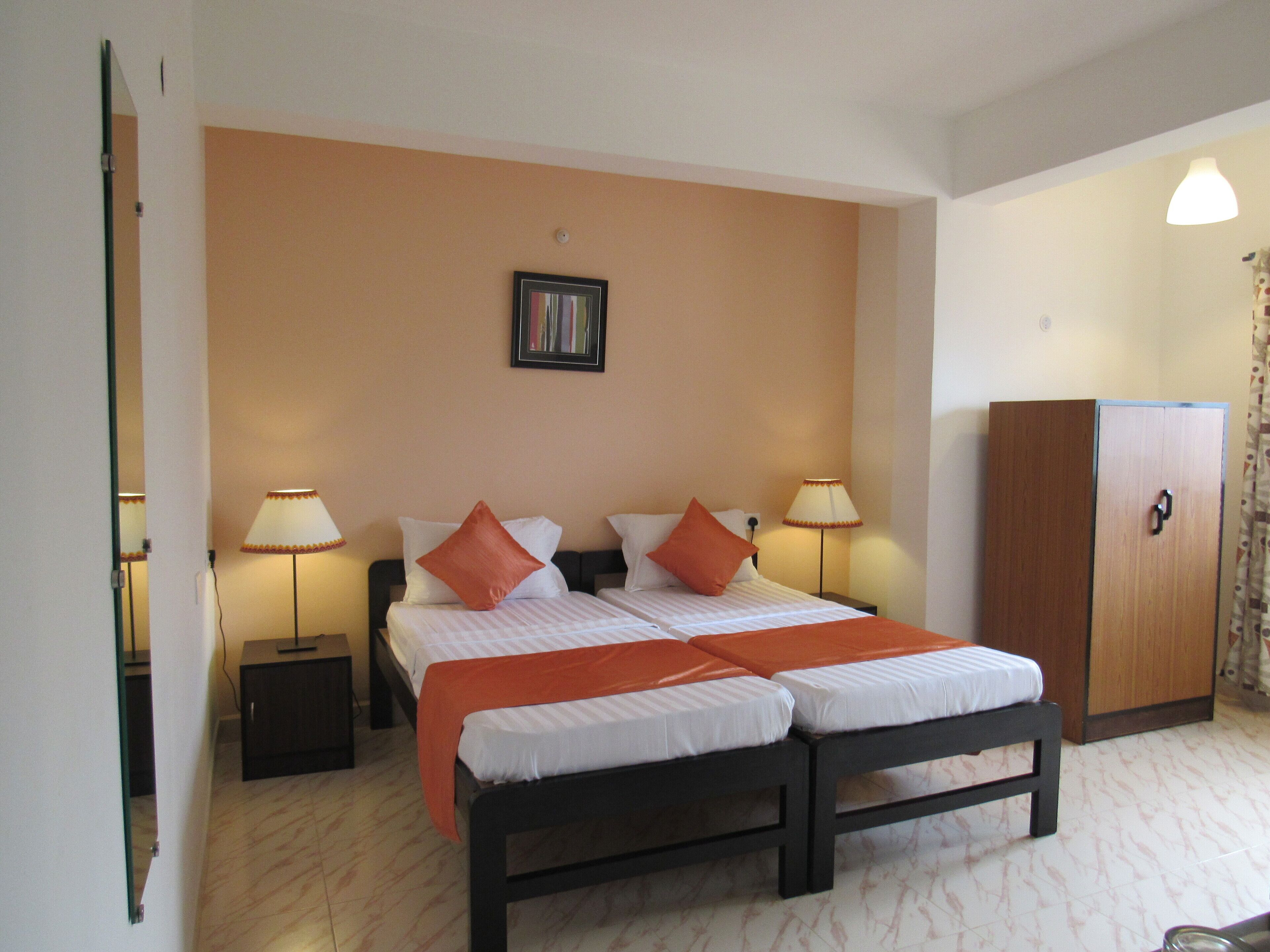 Une chambre d’hôtel avec un lit double, deux tables de chevet, une armoire et un tableau encadré au mur.