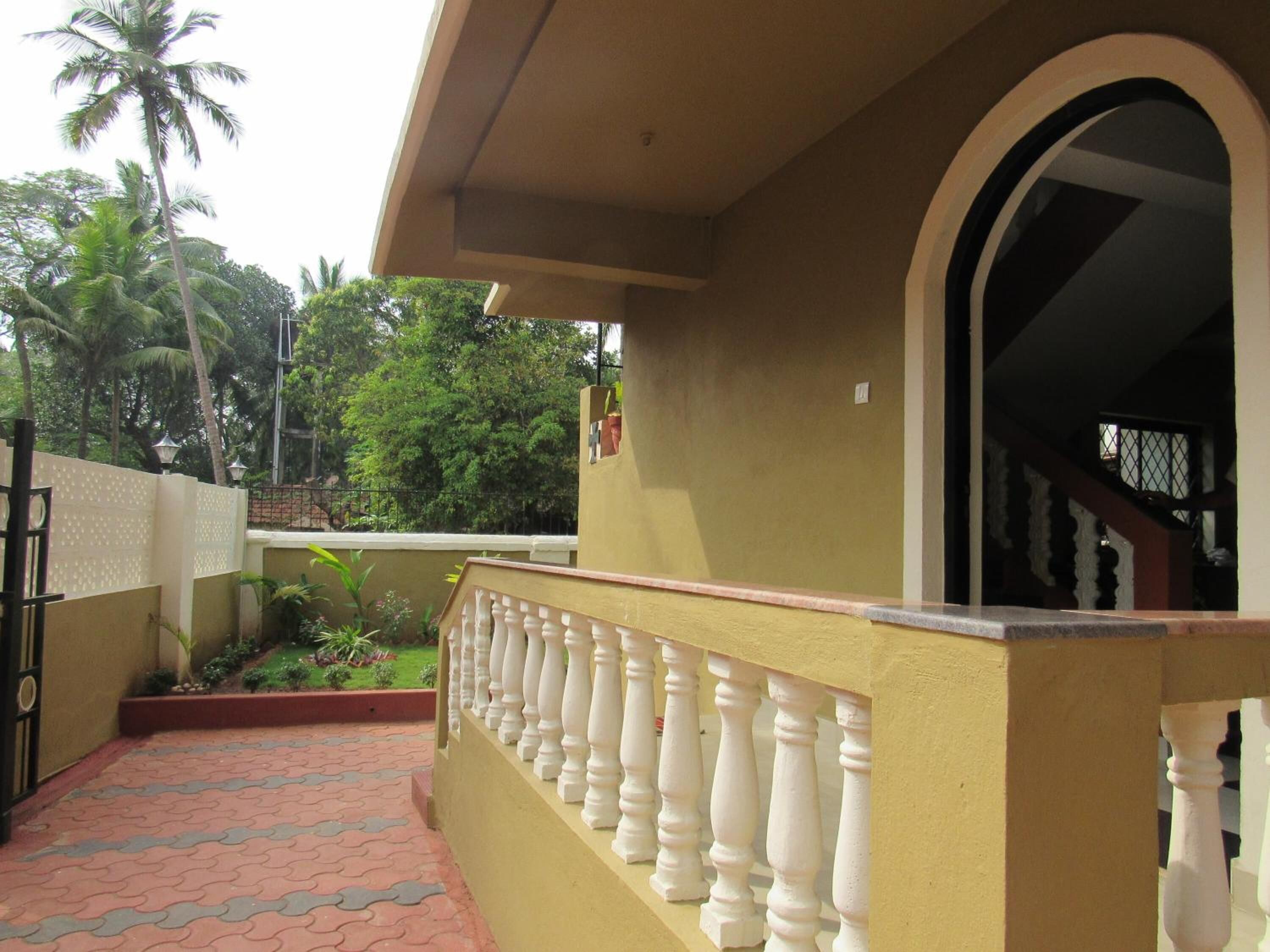 A building with a yellow exterior, a white balustrade, and a tiled walkway.