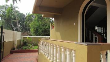 A building with a yellow exterior, a white balustrade, and a tiled walkway.