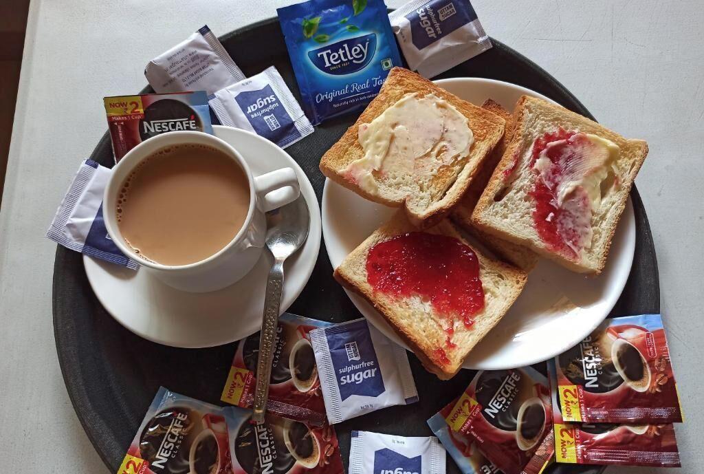 A tray with a cup of coffee, two slices of toast with jam, and various coffee pods.