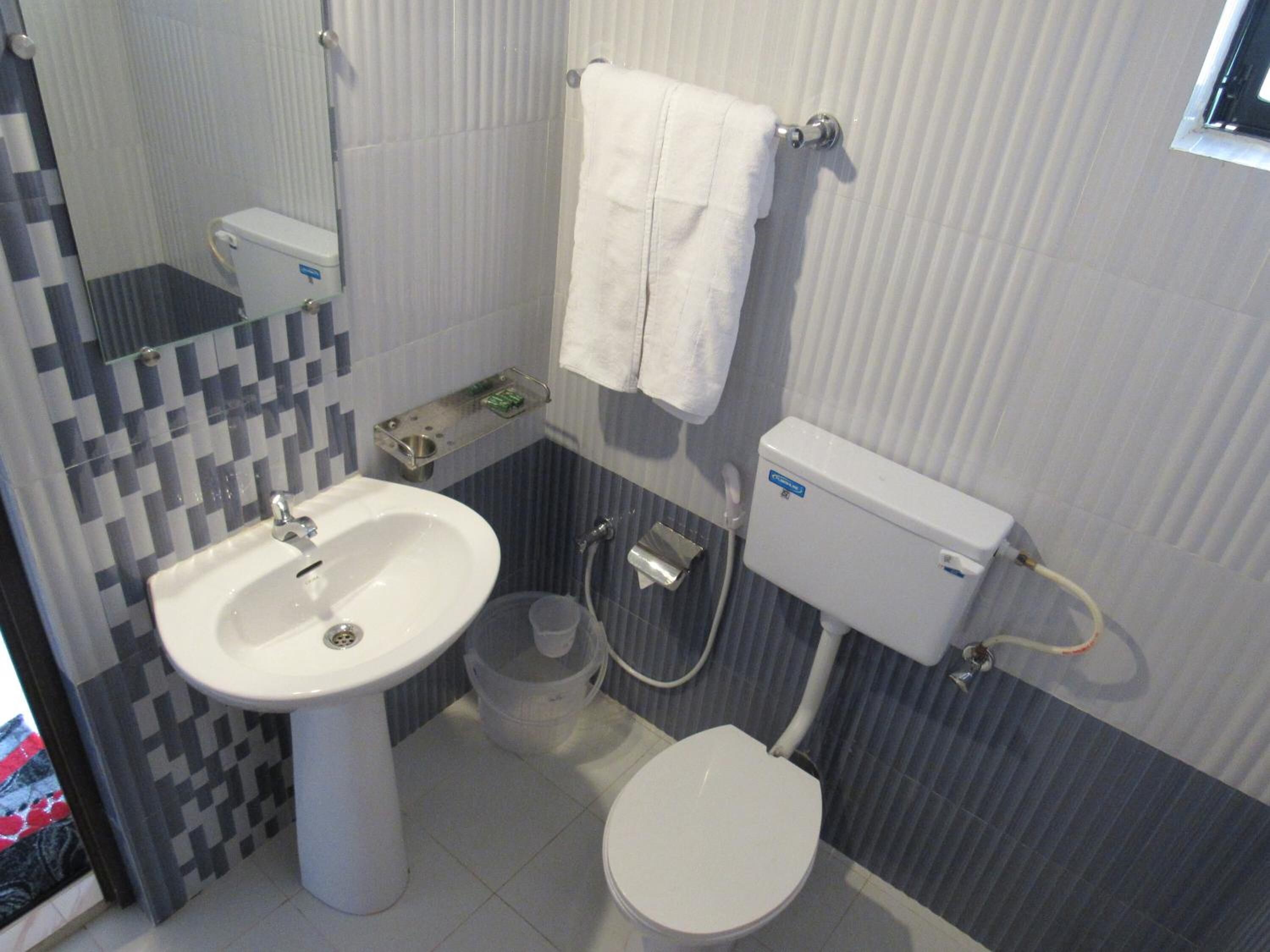 Un baño con lavamanos blanco, inodoro y una toalla colgada en la pared.
