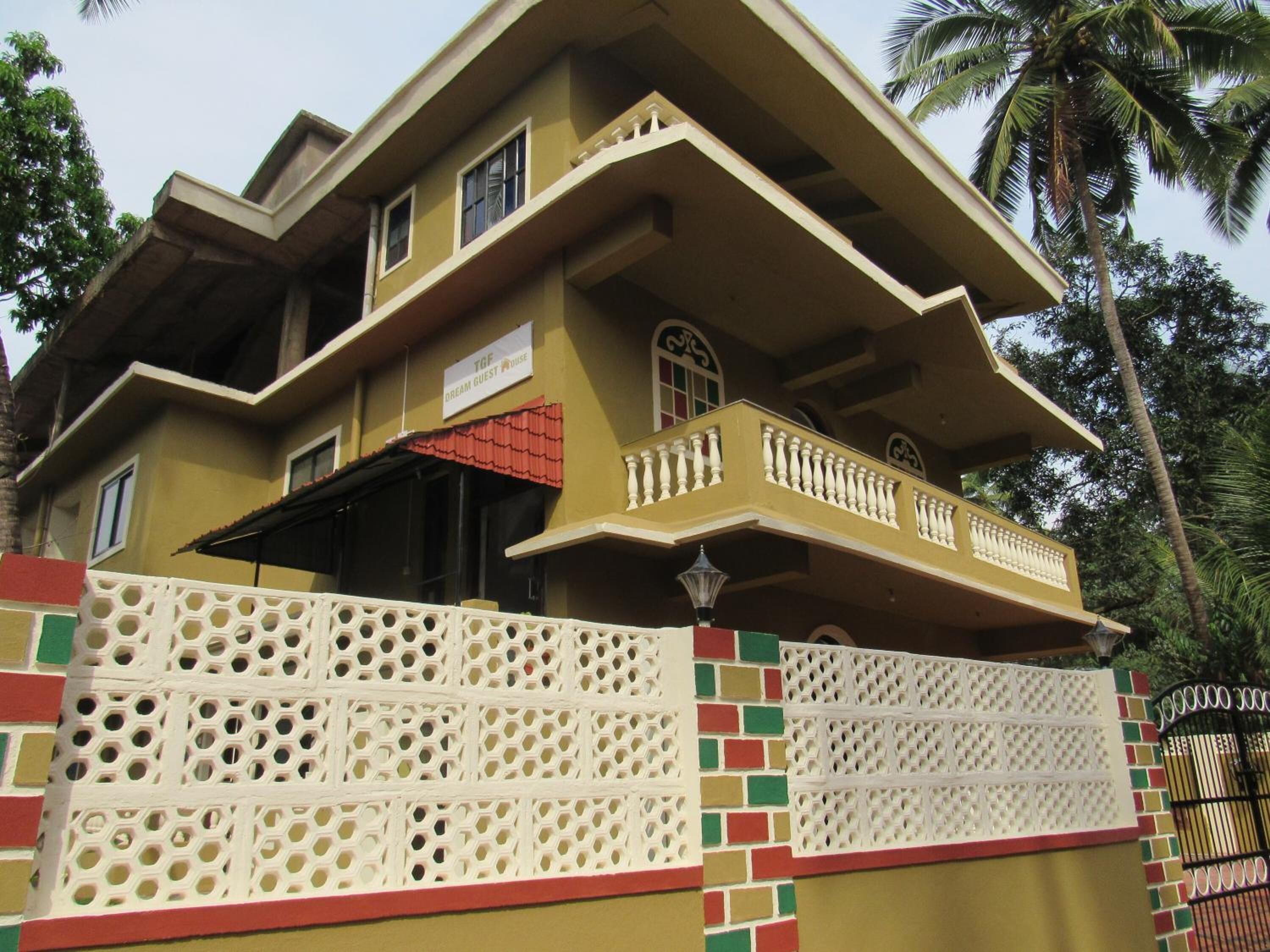 Un edificio de dos pisos con un balcón, un cartel que dice "Dream Guest House" y una valla decorativa.