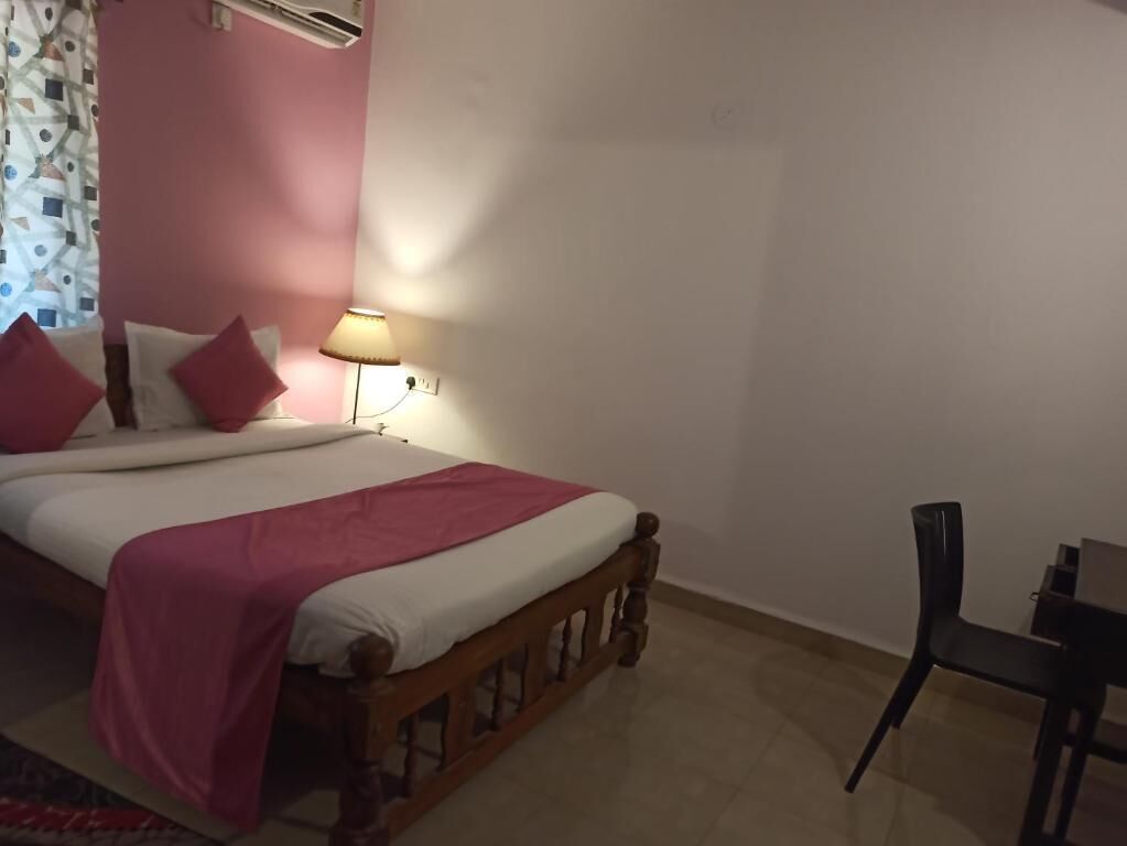 Un dormitorio con una cama, una silla y una lámpara de noche.