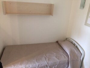 Una cama individual con colchón color crema y cabecera.