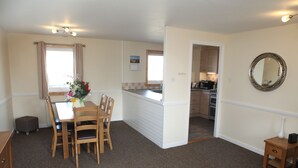 A compact kitchen with a dining area, a small side table, and a mirror on the wall.