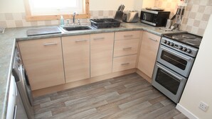A kitchen with wooden cabinets, a stainless steel stove, a microwave, and a sink.