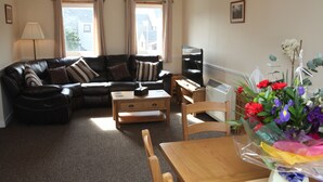 A living room with a sofa, a coffee table, a TV, and a bouquet of flowers.