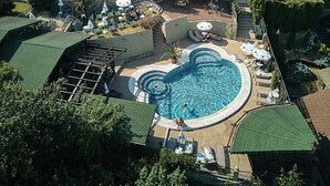 A hotel with a swimming pool, outdoor seating, and a view of the surrounding area. - Grand Hotel Belvedere Brasov (Brasov)