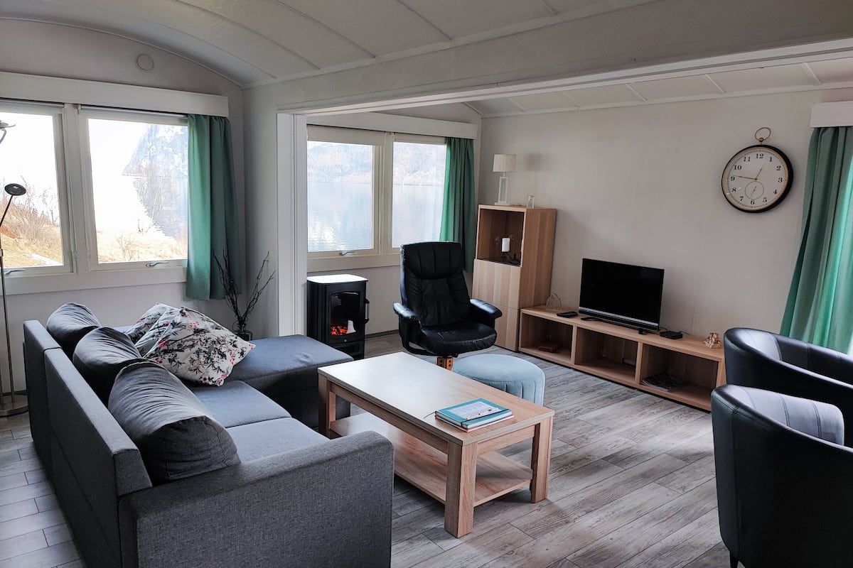 A modern living room with a sofa, armchair, coffee table, TV stand, and a fireplace.