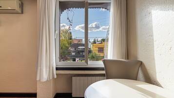 A hotel room with a window, a radiator, and a chair.