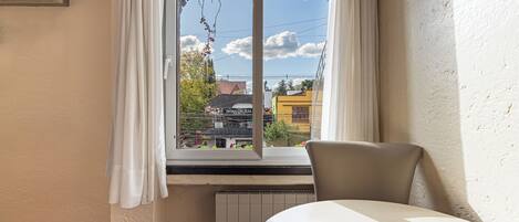 Una habitación de hotel con ventana, radiador y una silla.