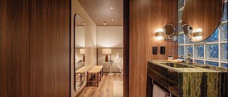 A modern bathroom with wooden walls, a marble sink, and a large mirror.
