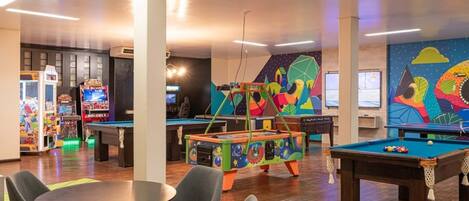 A recreational area with pool tables, arcade games, and colorful murals.