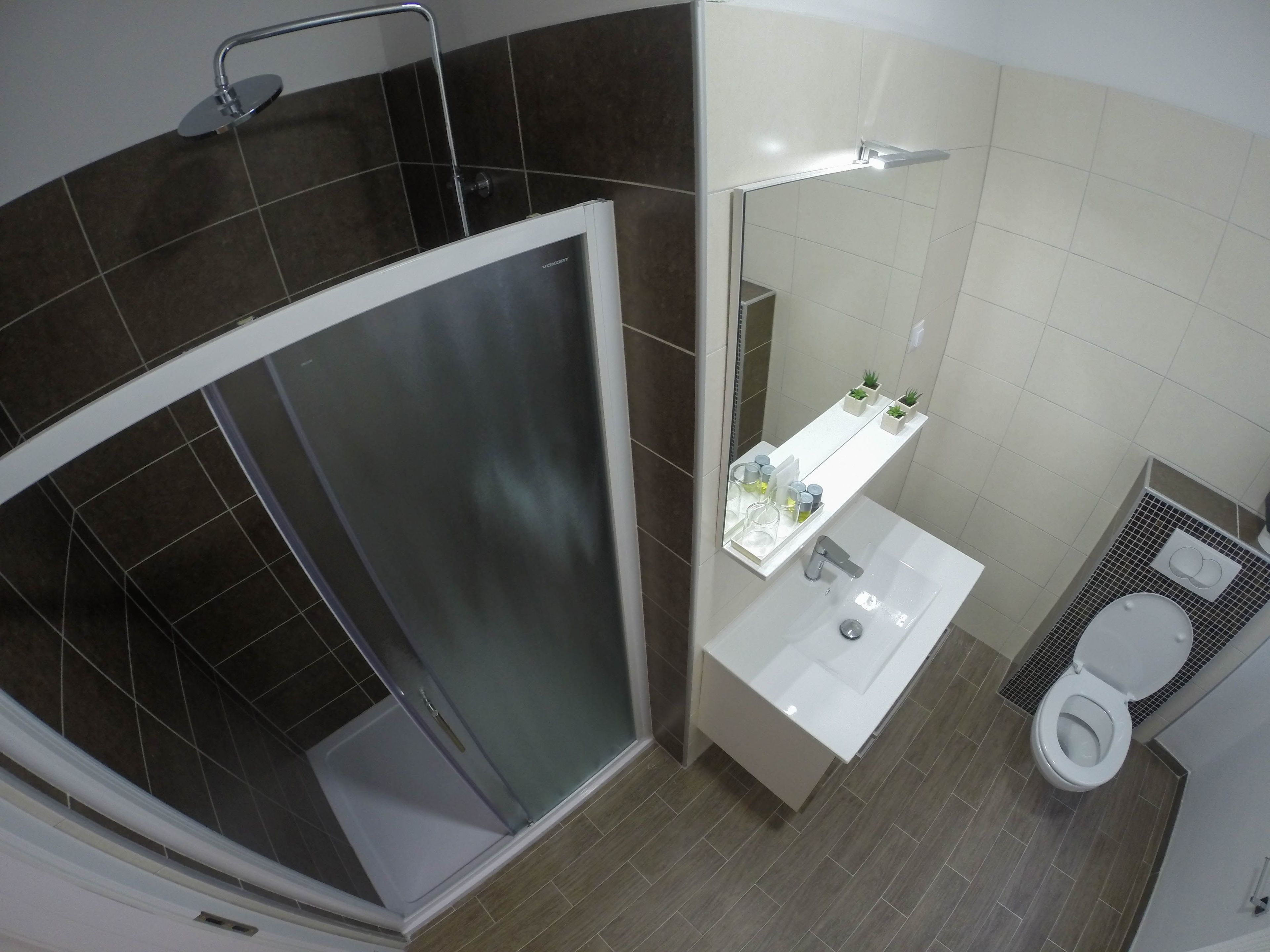 A modern bathroom with a glass-enclosed shower, a white sink, and a toilet.