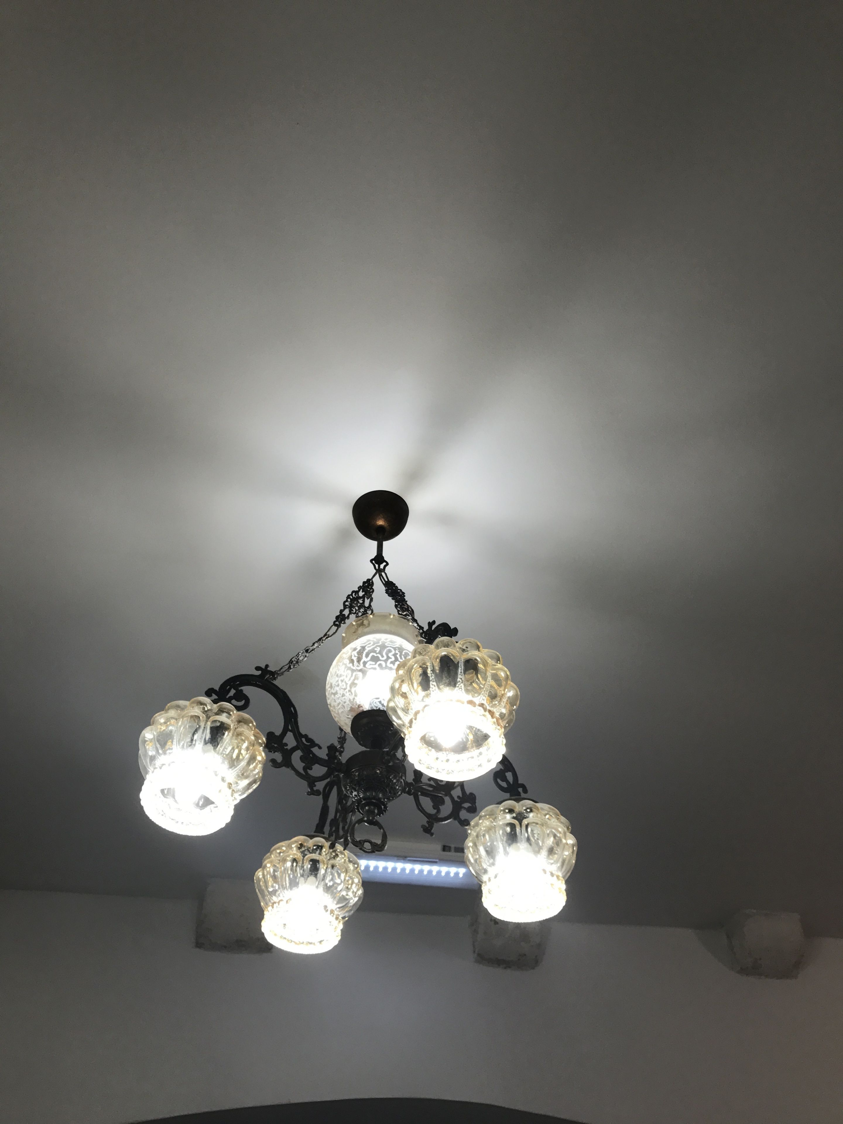 Un lampadari amb diverses llanternes de vidre i una esfera fosca al centre, penjant d'una estructura de metall negre.