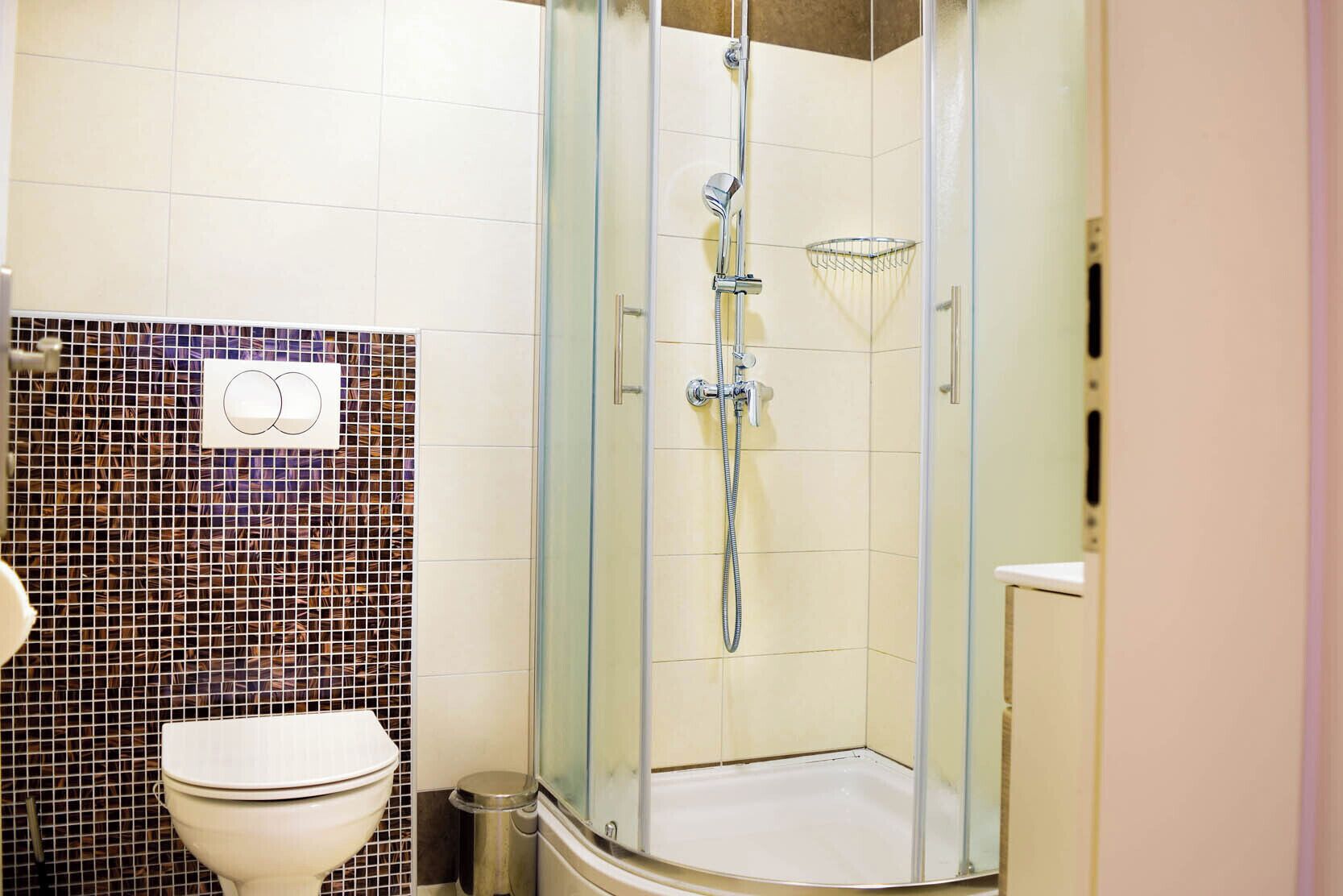 A bathroom with a glass-enclosed shower, a toilet, and a tiled wall.