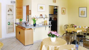 A compact kitchen with a dining area, featuring a wooden cabinet, a countertop with various kitchen items, and a dining table with chairs.