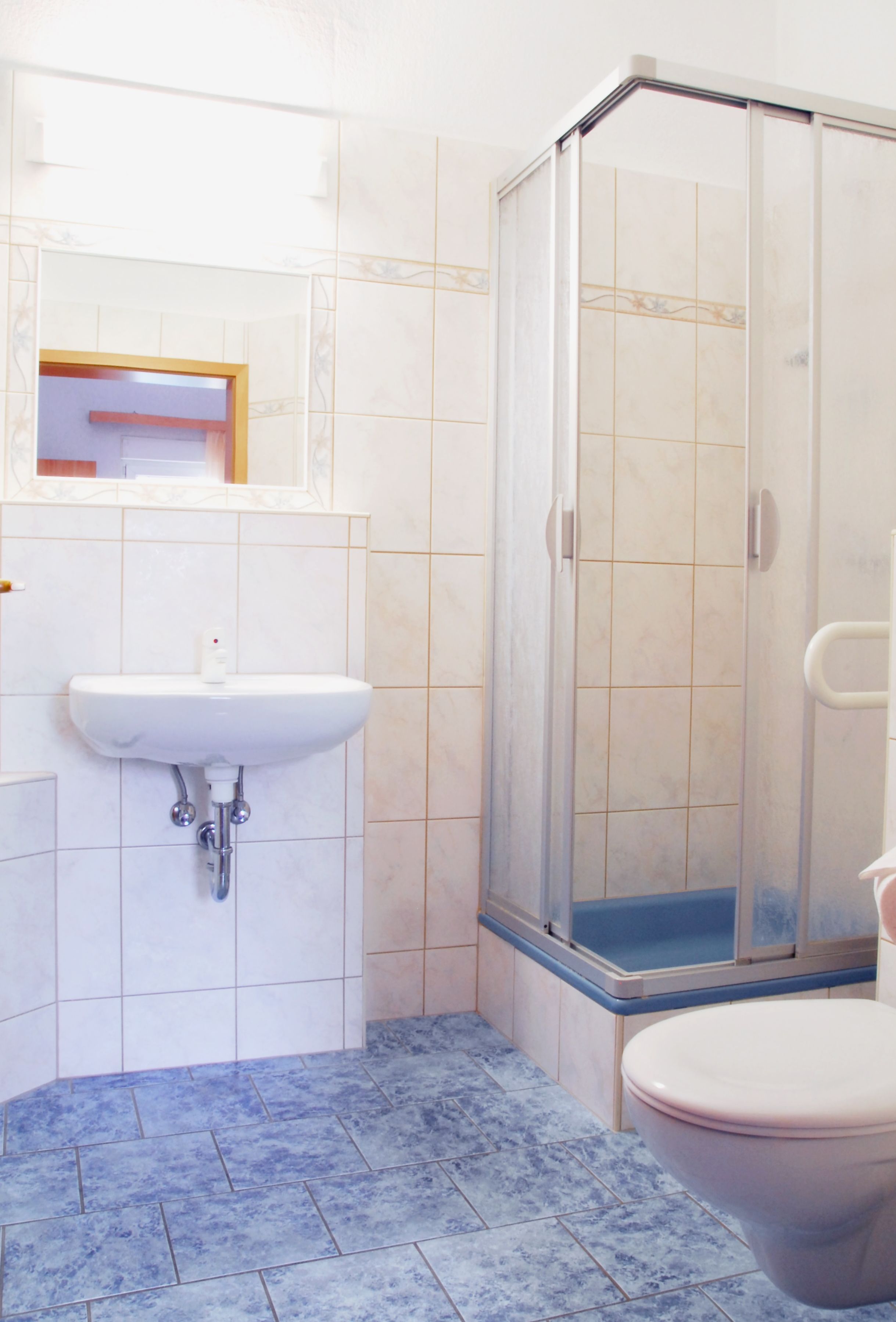 A bathroom with a white sink, a toilet, and a glass shower enclosure.