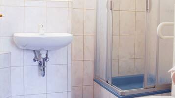 A bathroom with a white sink, a toilet, and a glass shower enclosure.