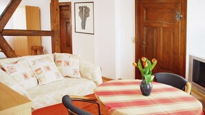 A cozy room with a bed, a dining table with a vase of flowers, and a wooden door.