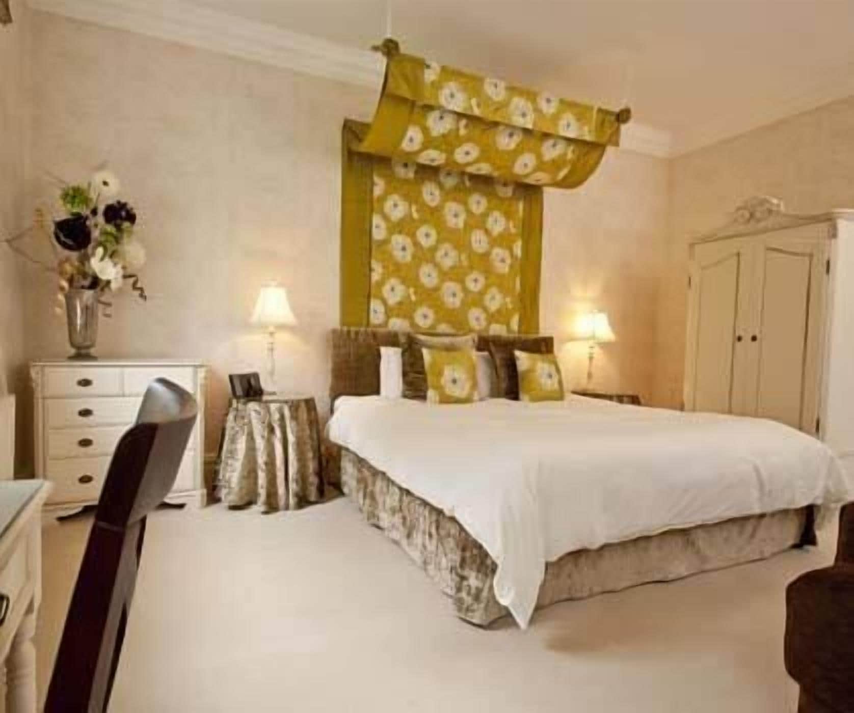 A bedroom with a bed, bedside tables, lamps, a dresser, and a wardrobe.