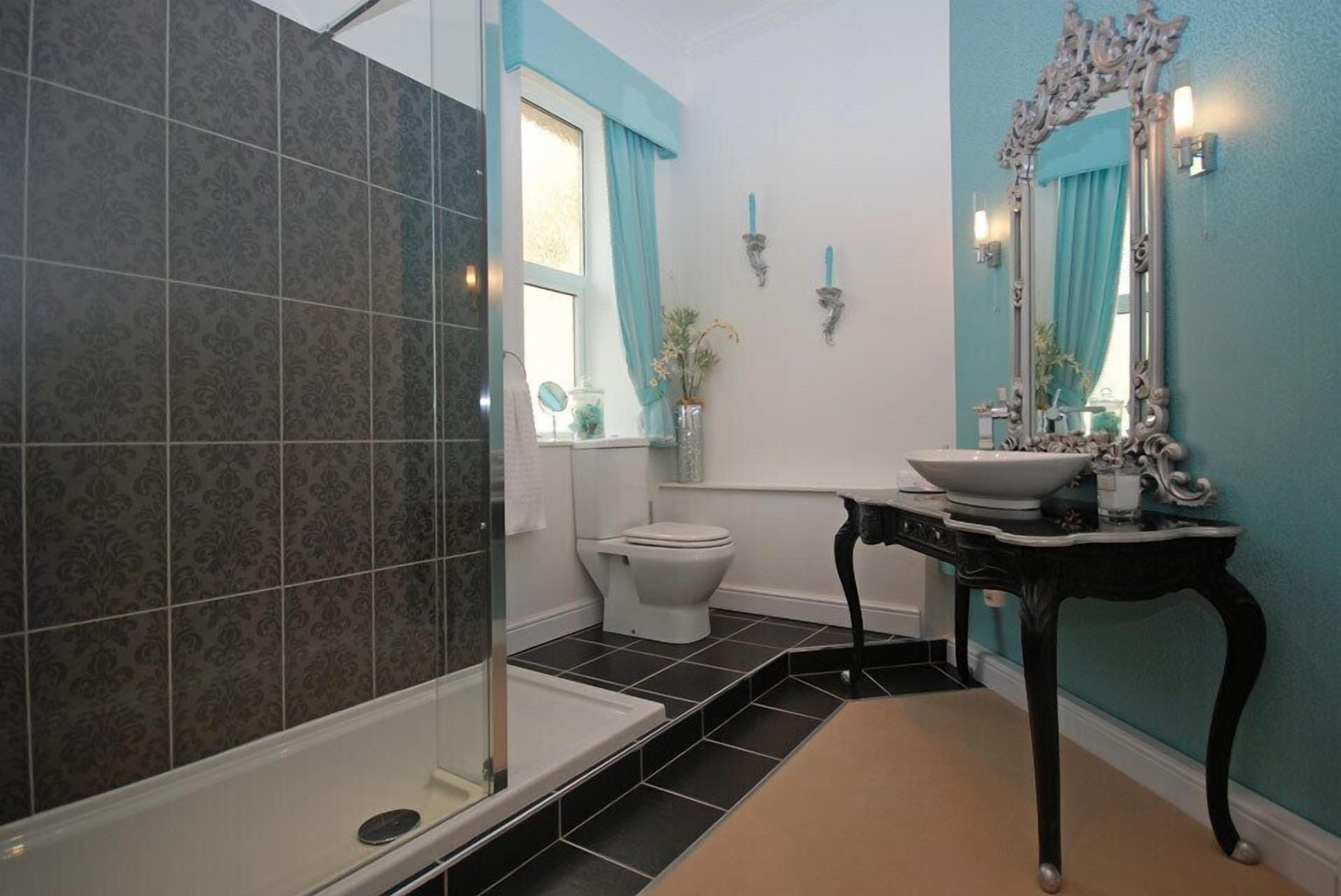 A bathroom with a shower, toilet, sink, and a large mirror.