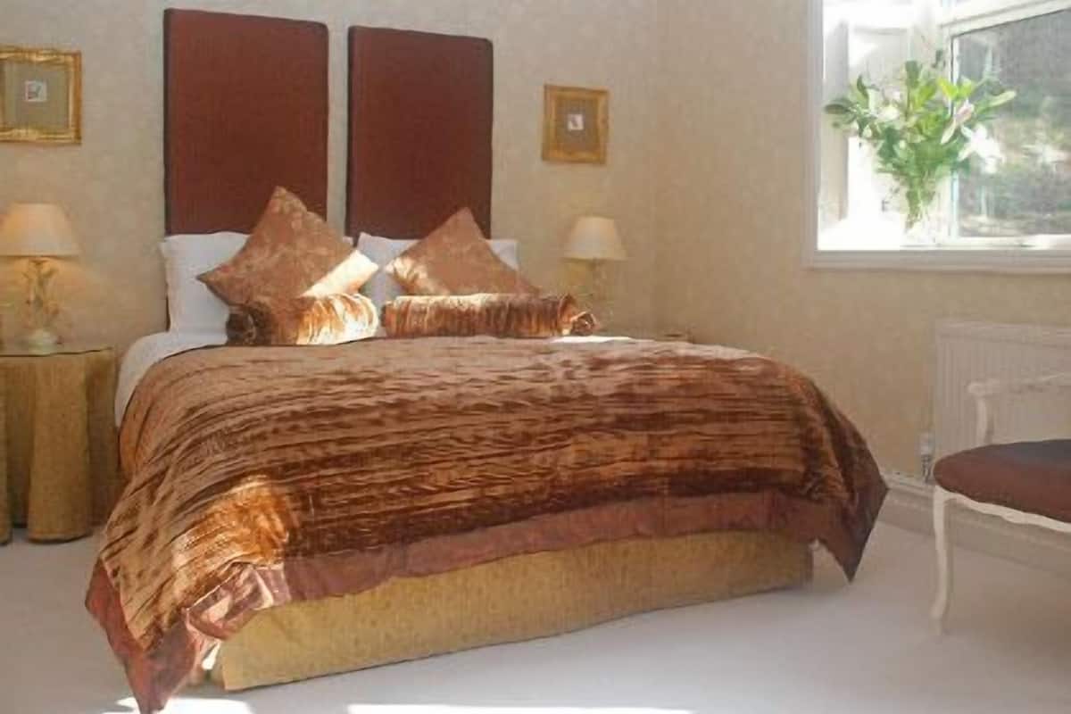 A bedroom with a large bed, two bedside tables, a window with a view, and a chair.