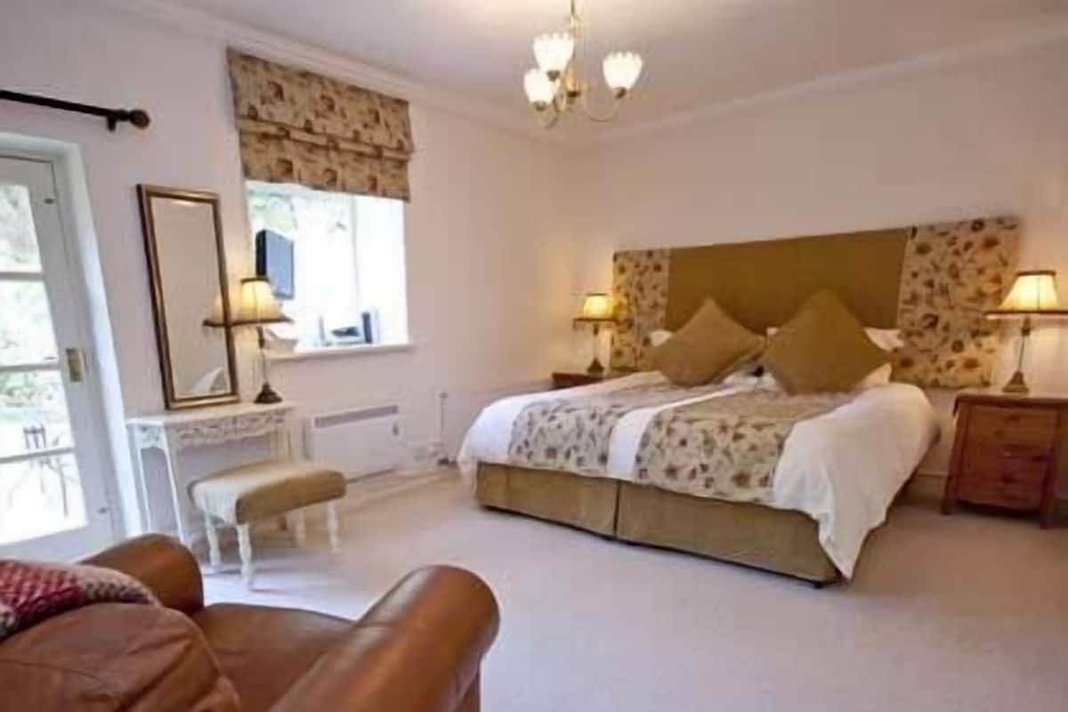 A bedroom with a large bed, bedside tables, a bench, and a chair.