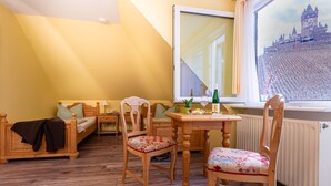 A cozy room with a bed, a table with a bottle, and a chair. - Villa Tummelchen (Cochem)