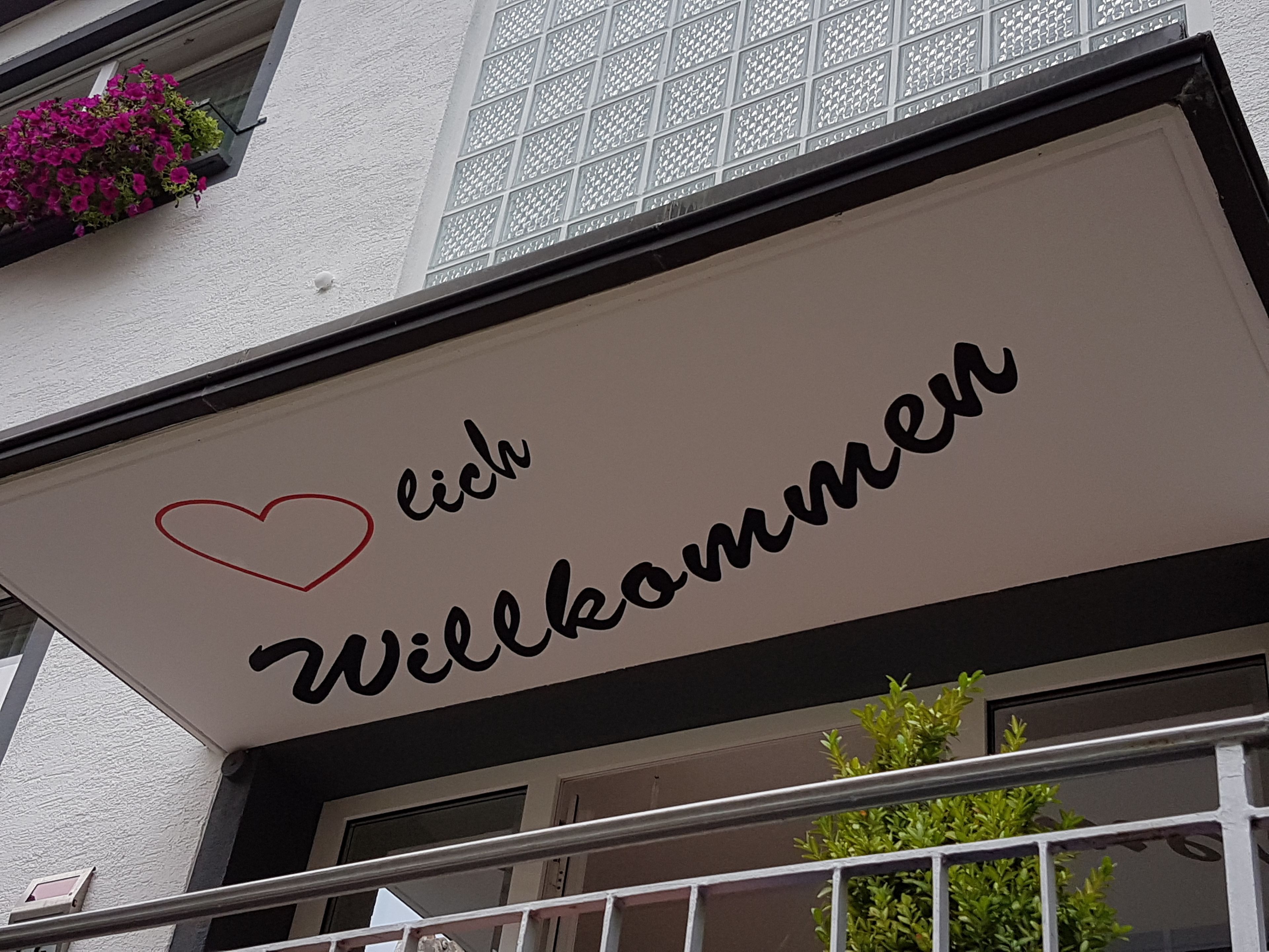 A sign with the text "Willkommen" and a heart symbol.