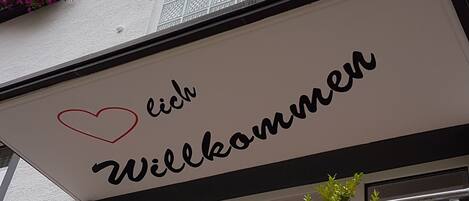 A sign with the text "Willkommen" and a heart symbol.