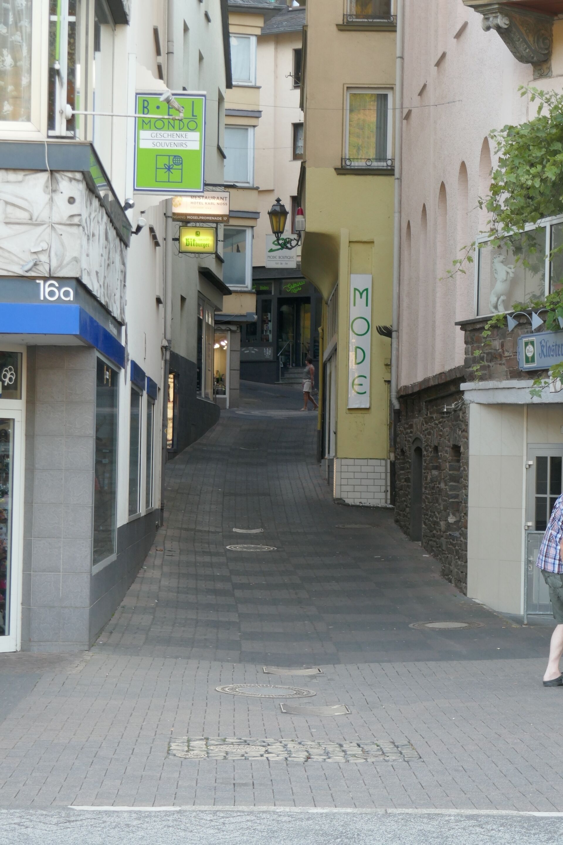 A narrow street with buildings on either side, including a sign for 'B&B MONDO' and a 'MODE' sign.