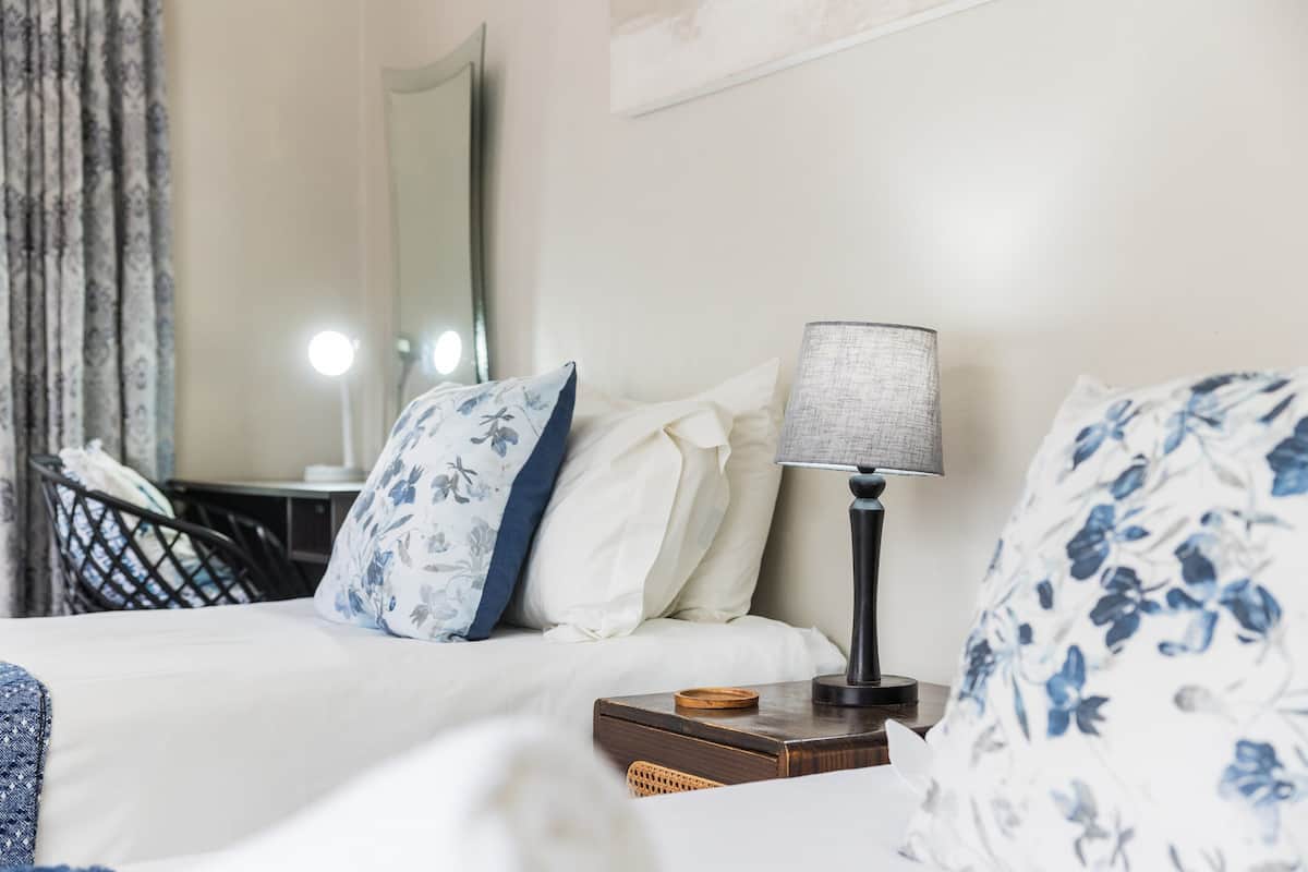 A neatly made bed with floral pillows, a bedside lamp, and a small wooden box on the nightstand.