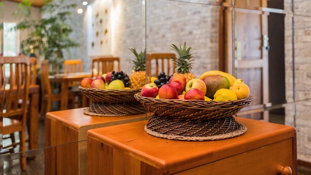 Dos cestas de mimbre con fruta sobre una mesa de madera en un restaurante con paredes de ladrillo y sillas de madera.