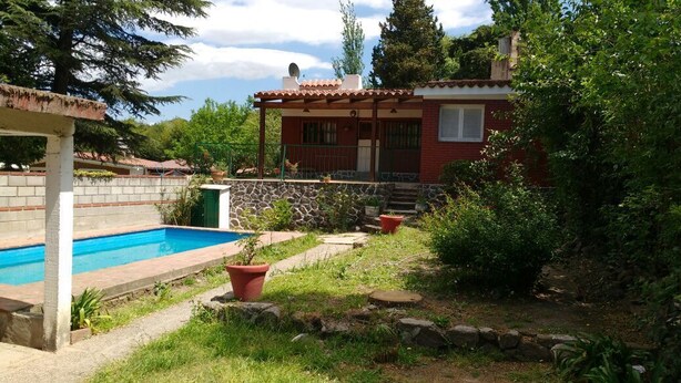 Une maison avec une piscine, un mur en pierre et un jardin agrémenté de plantes en pot.
