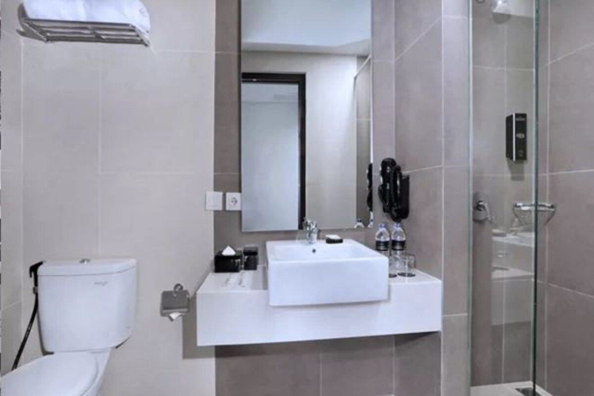 A modern bathroom with a white sink, mirror, and toilet.
