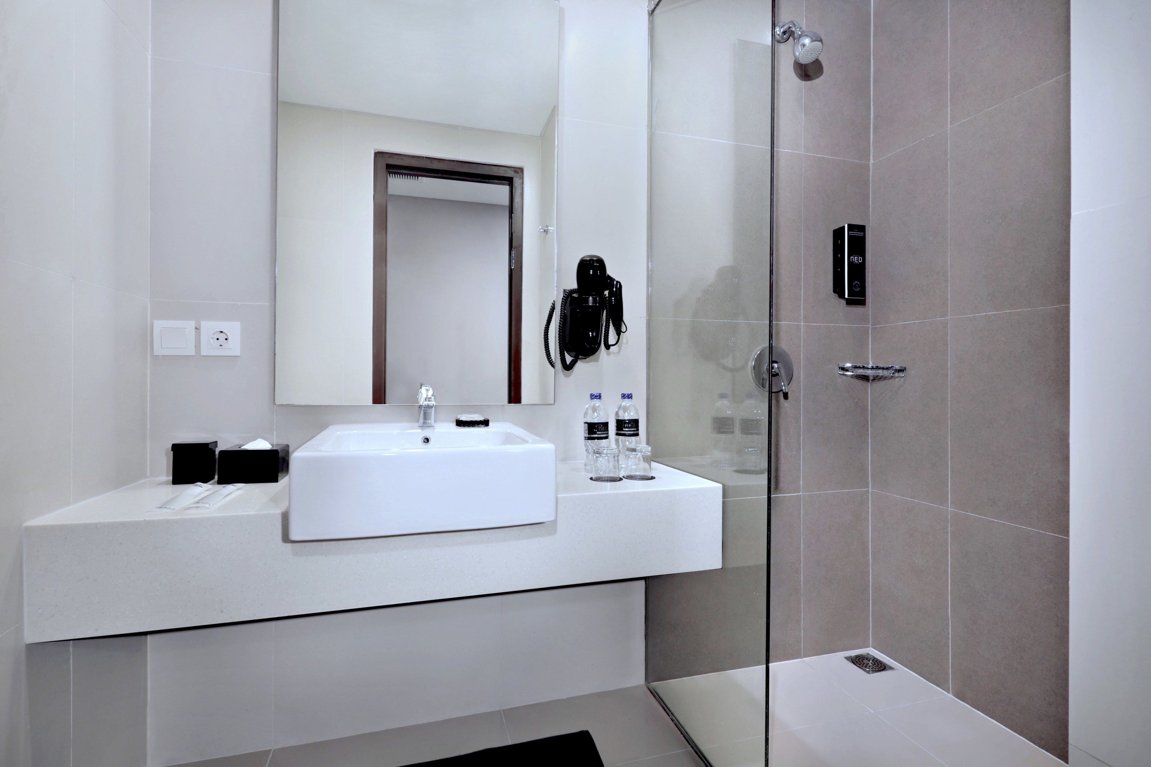 A modern bathroom with a white sink, mirror, and shower.