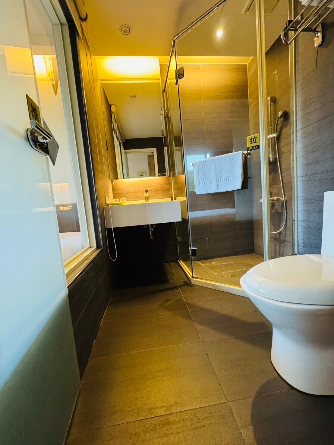 Un baño moderno con ducha envuelta en vidrio, un inodoro blanco y un lavamanos con espejo.