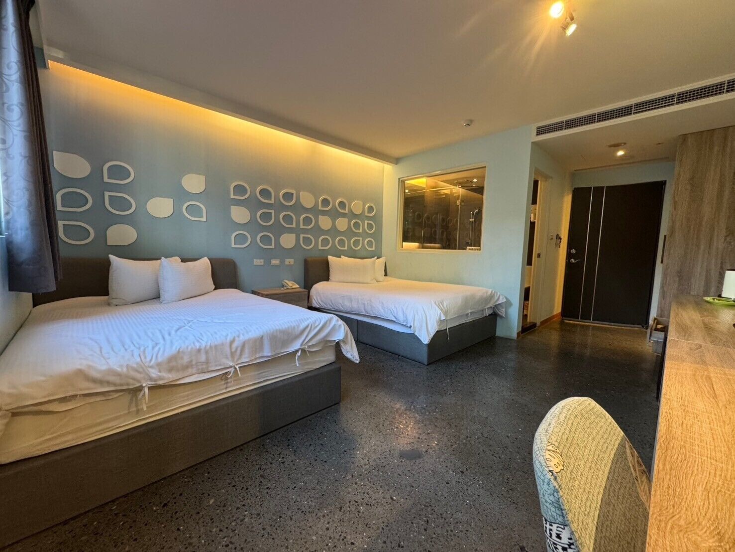 Een moderne hotelkamer met twee bedden, een grote spiegel en een opvallend wandontwerp.