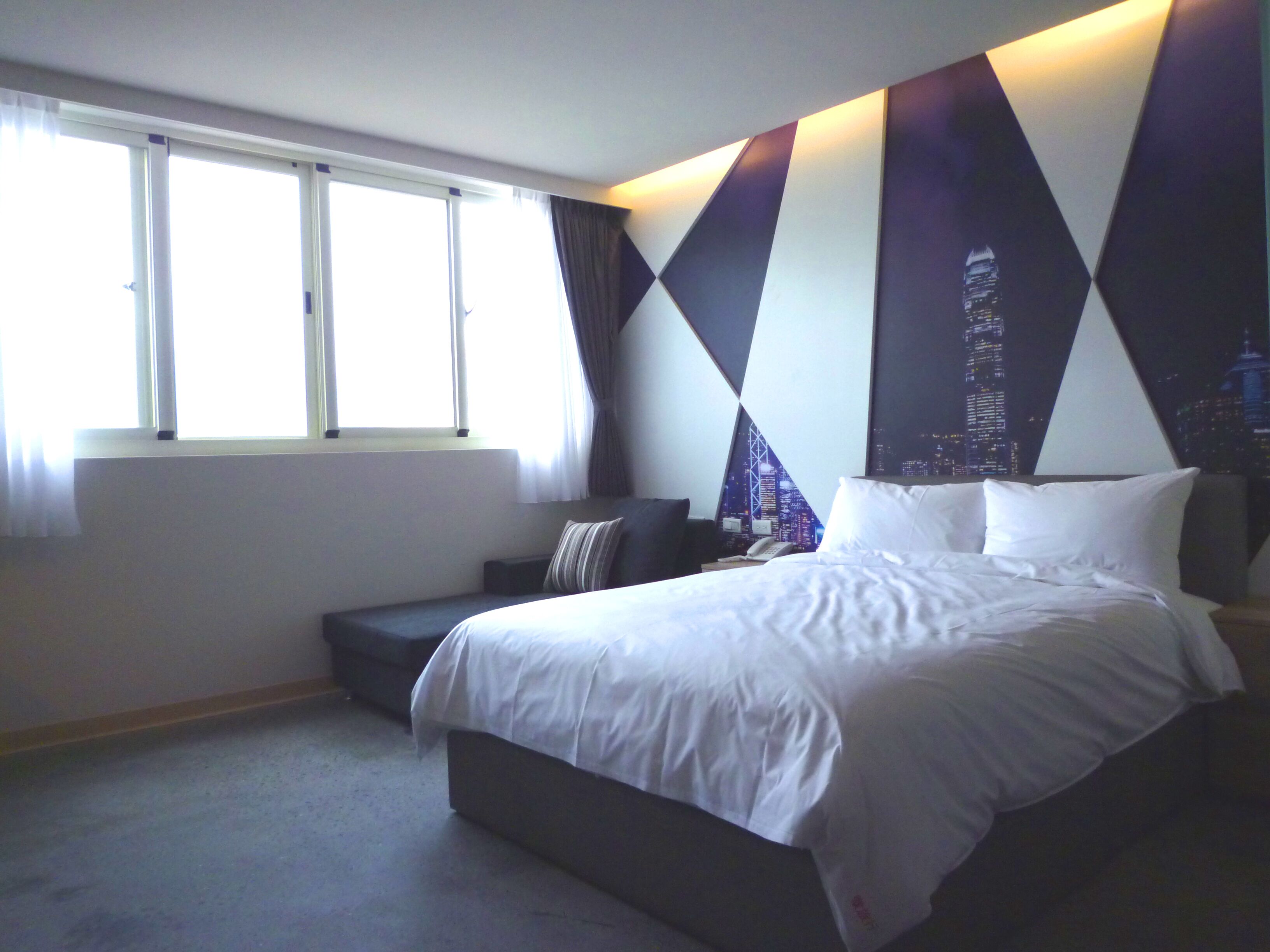 Une chambre d’hôtel moderne dotée d’un grand lit, d’un coin salon et offrant une vue sur la ville.