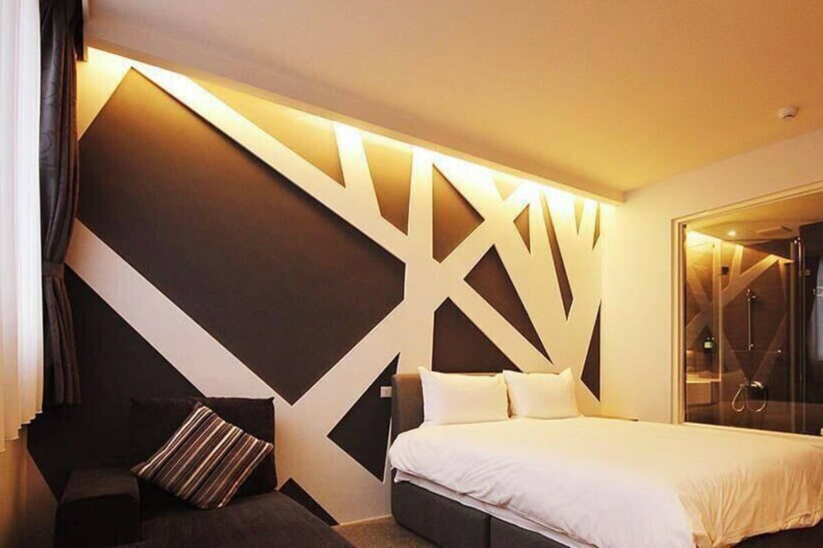 Una habitación de hotel moderna con una cama, un área de descanso y una ducha de vidrio.